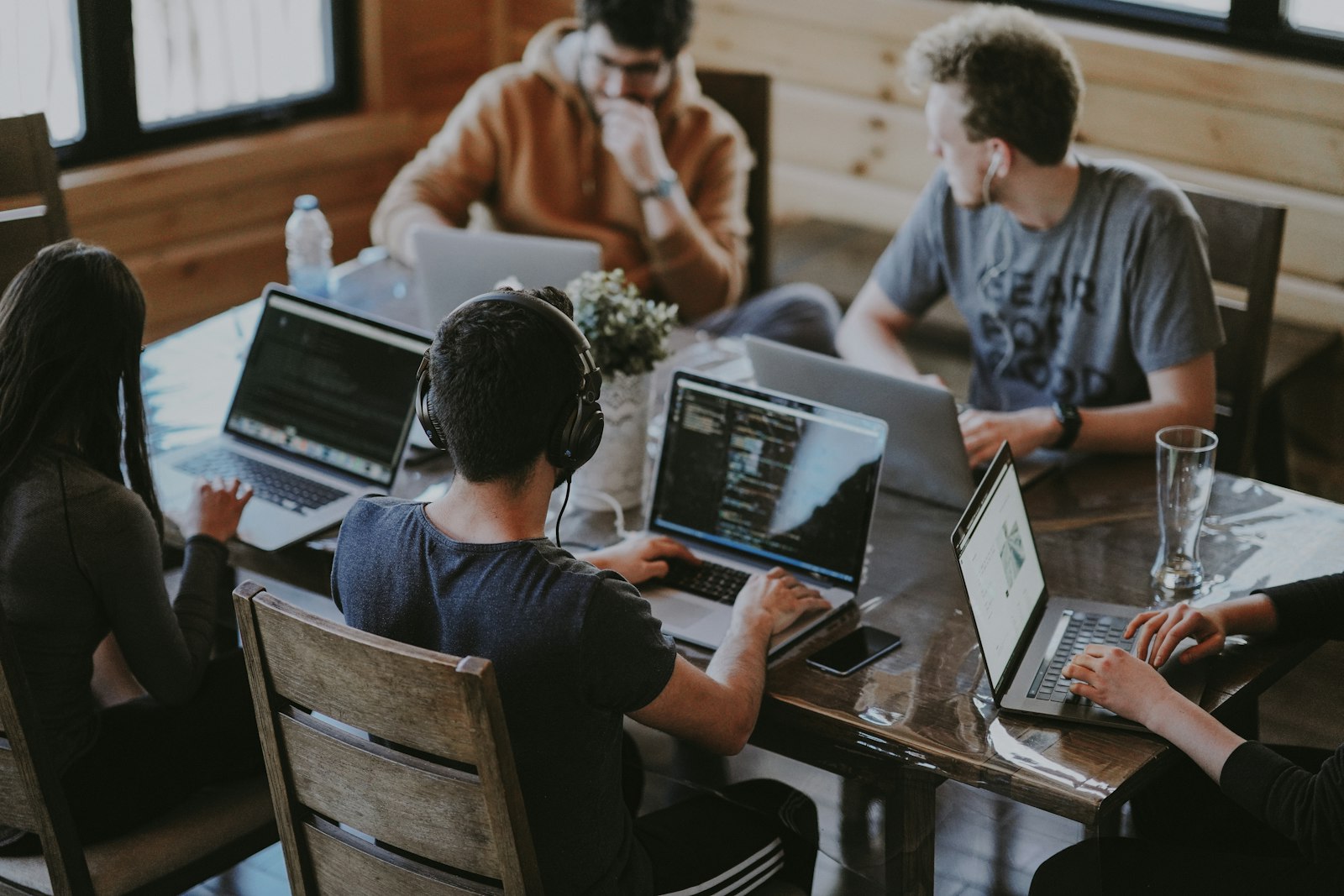 Equipo de desarrollo trabajando con laptops alrededor de una mesa
