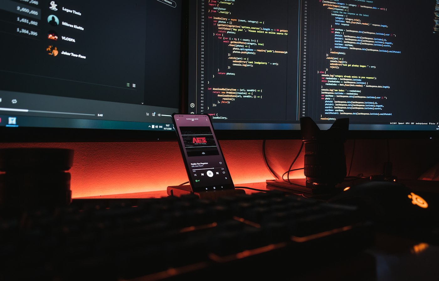 Escritorio con monitores de código y un teléfono en un soporte